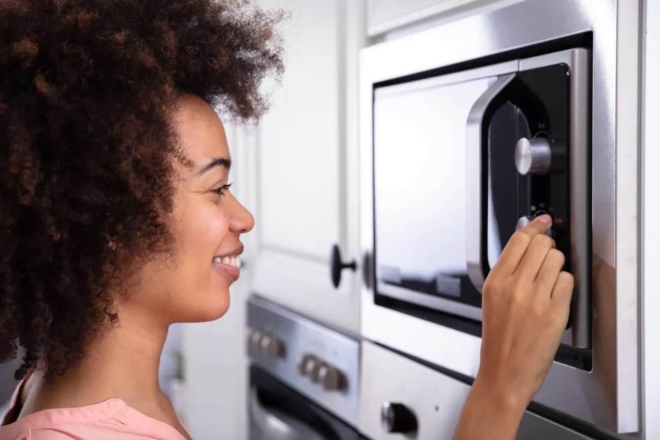 woman typing on microwave buttons