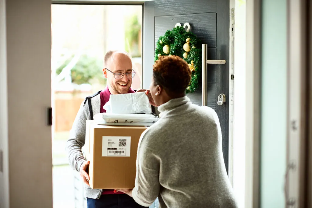 Delivery man handing over cardboard box to female customer, Christmas time, Christmas delivery, online shopping