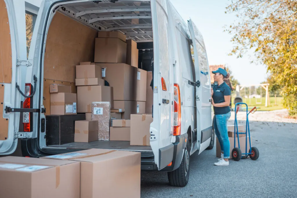 Mixed race female worker taking packages from the delivery van