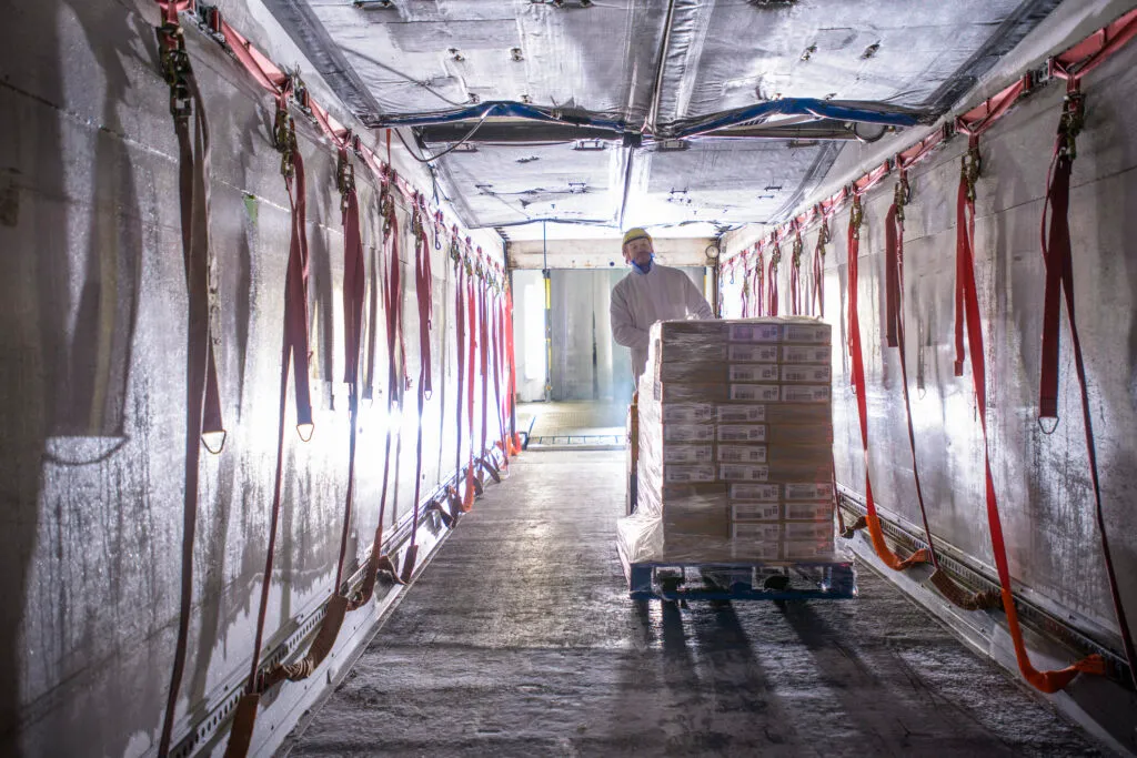 Worker loading products into freezer truck of food factory