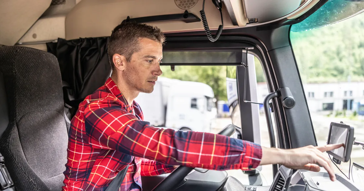 Truck driver behind the steering wheel sets navigation for his next journey on a GPS device.