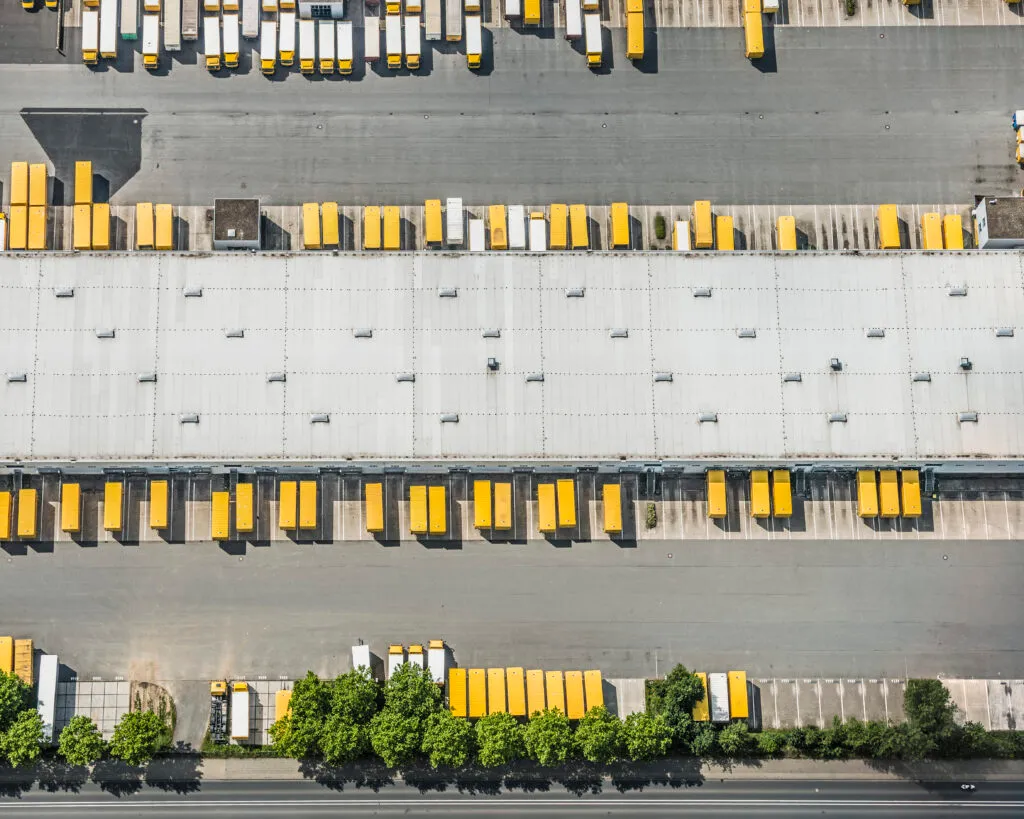 Postal logistics center with parked yellow trucks and truck trailers, aerial view