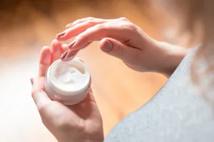 woman dipping hand in moisturizer