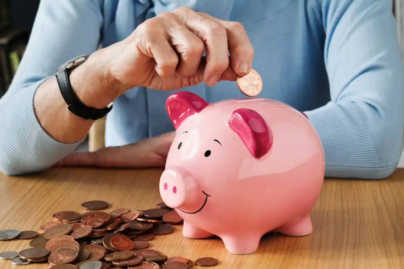 Retired Woman Putting Money in Piggy Bank