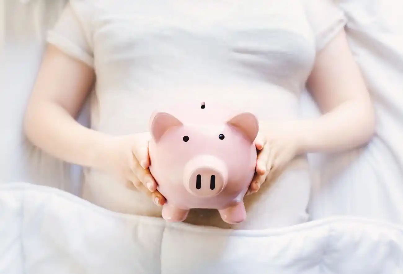 Woman Lying in Bed with Piggy Bank