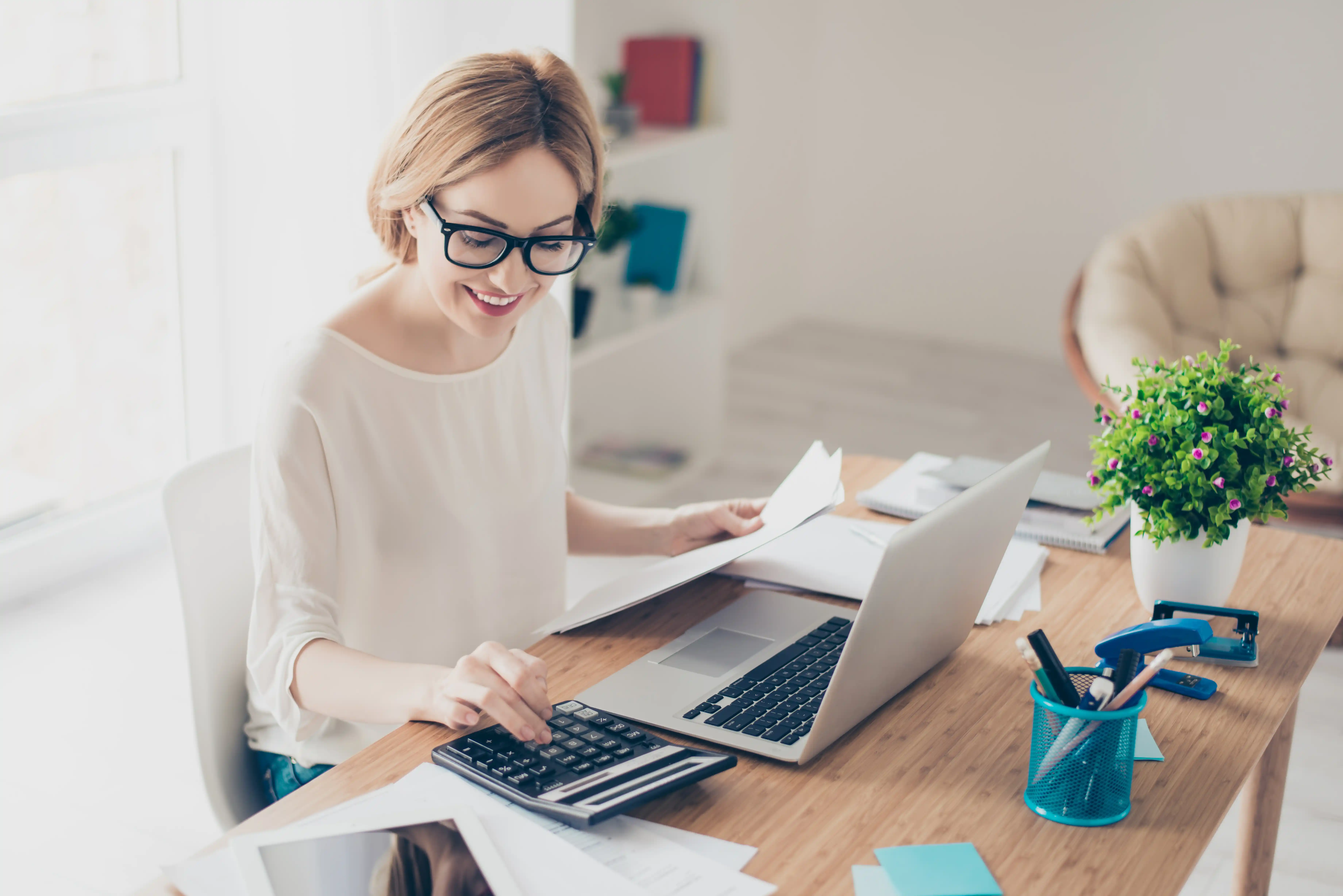 Female bookkeeper working with laptop and calculator