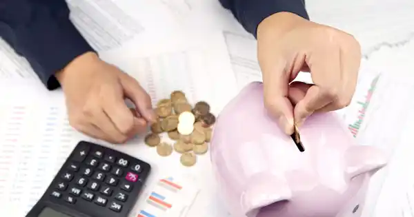 Woman Putting Coins in Piggy Bank