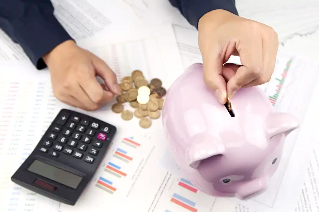 Woman Putting Coins in Piggy Bank