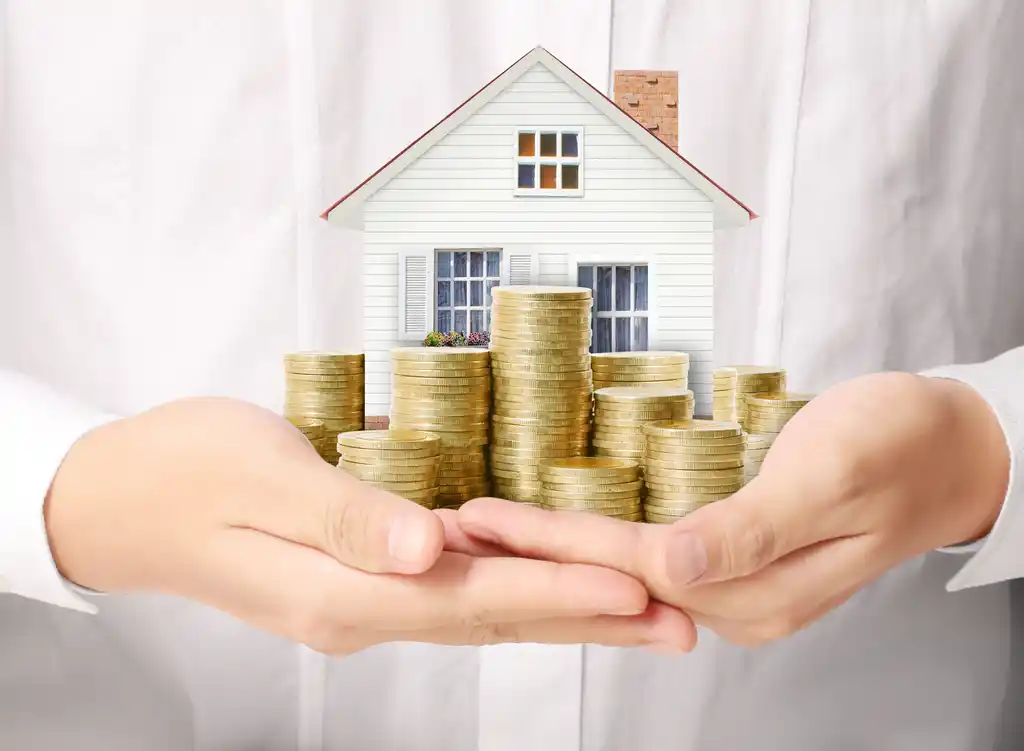 Woman Holding Little House and Gold Coin Stacks