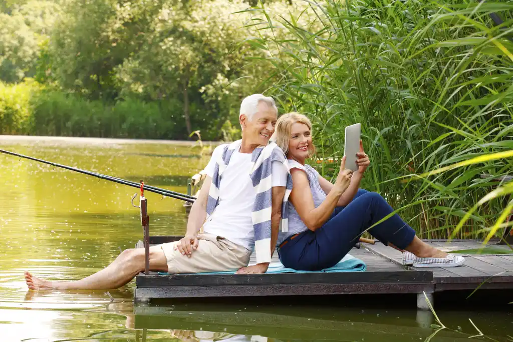 Retired Couple Relaxing on Dock with Tablet