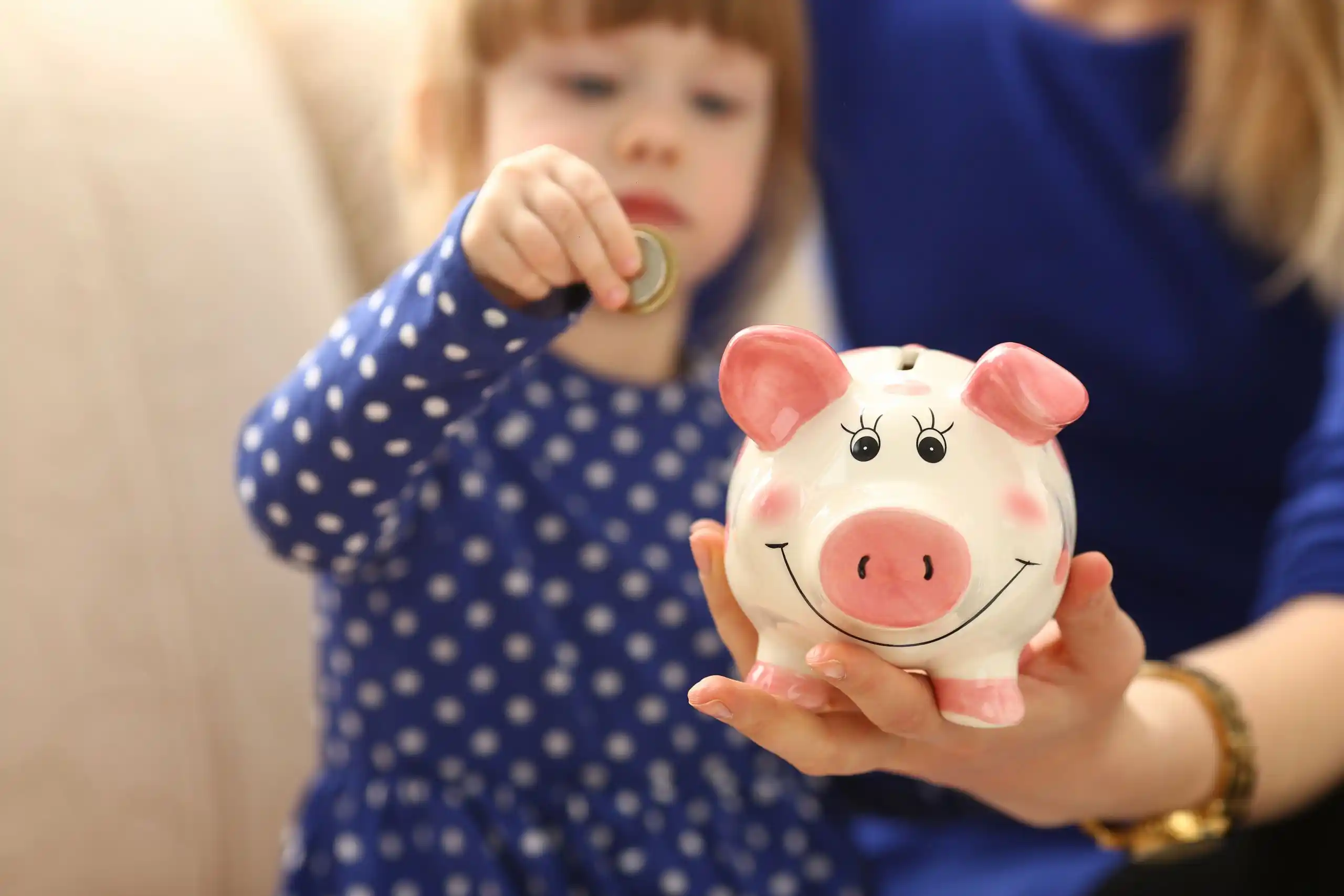 Kid Putting Money in Piggy Bank