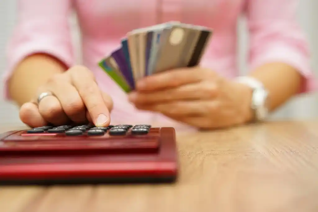 Woman Typing on Calculator with Credit Cards in Hand