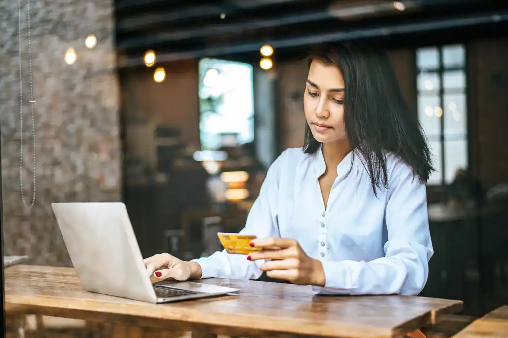 Woman with Laptop Looking Sad at Credit Card