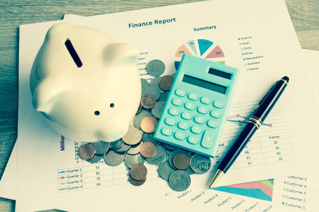Piggy Bank and Calculator on Top of Finance Report