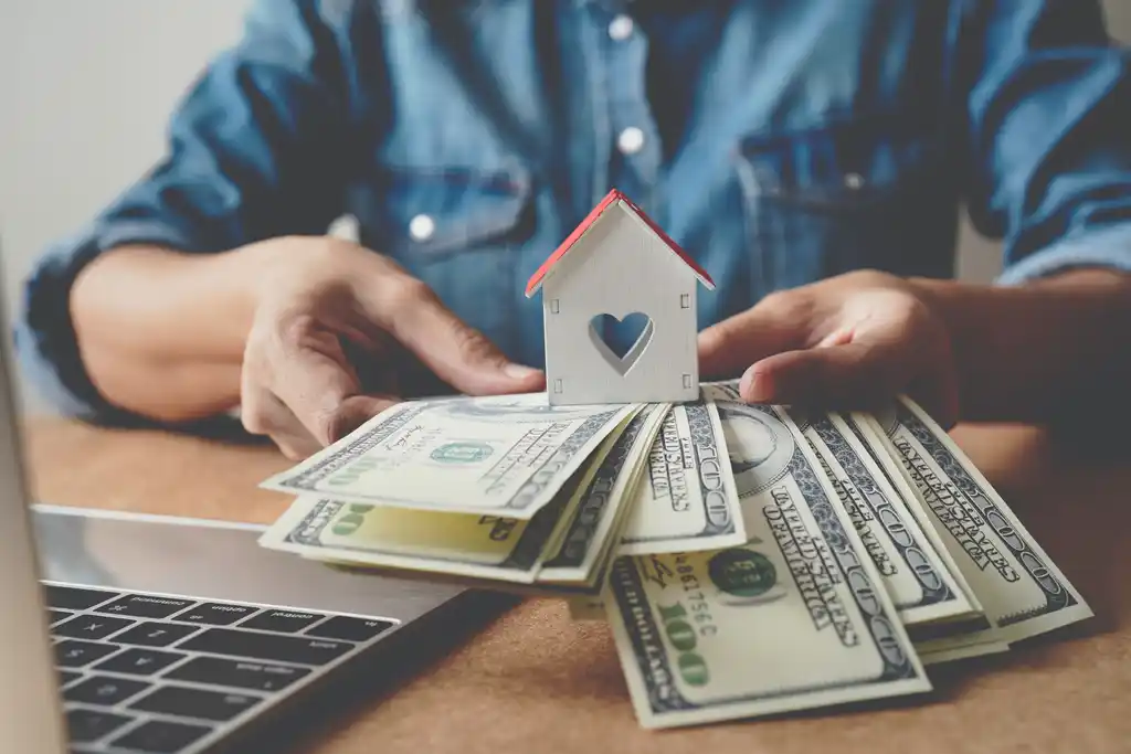 Man Holding Mini Home & Money