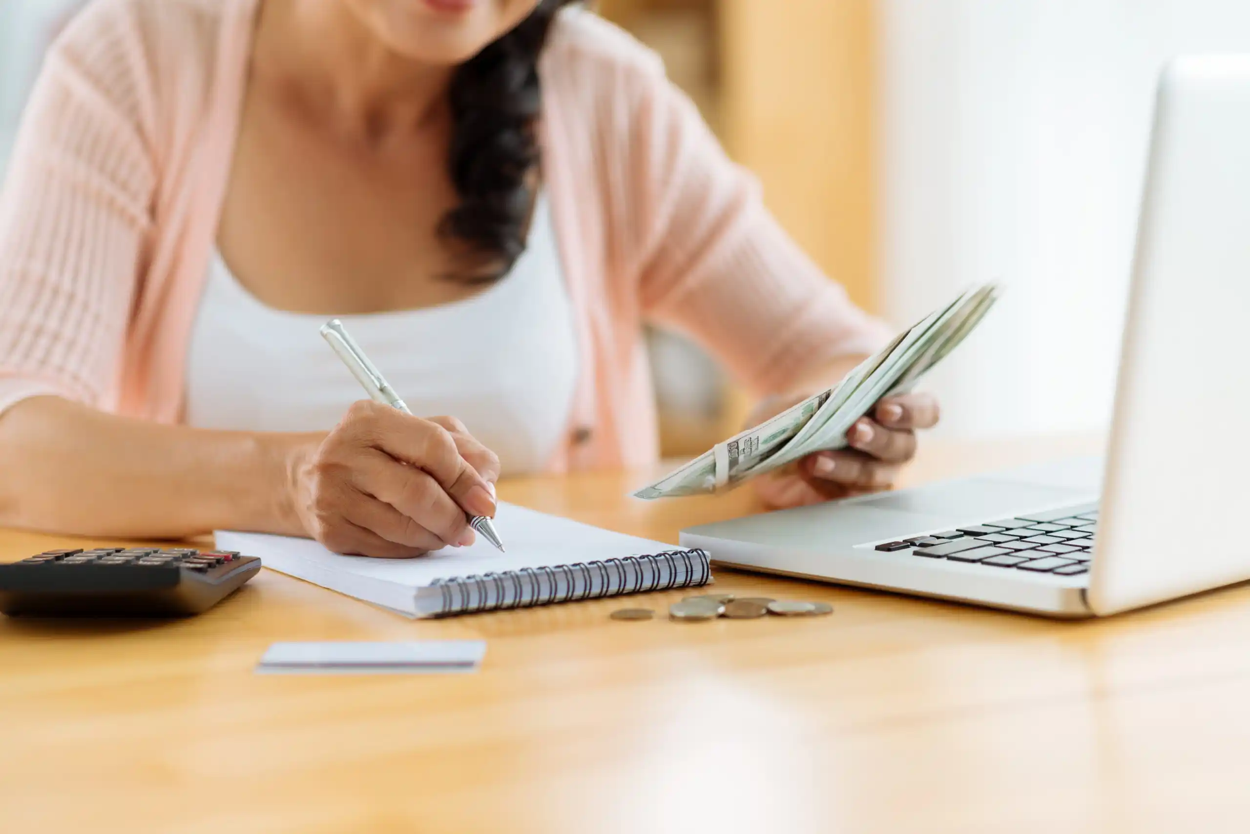 Woman Recording Cash Spent on Notepad