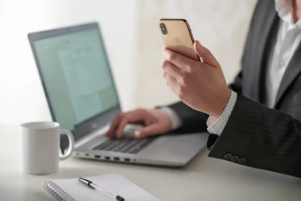 Man Looking at Website on Phone and Laptop