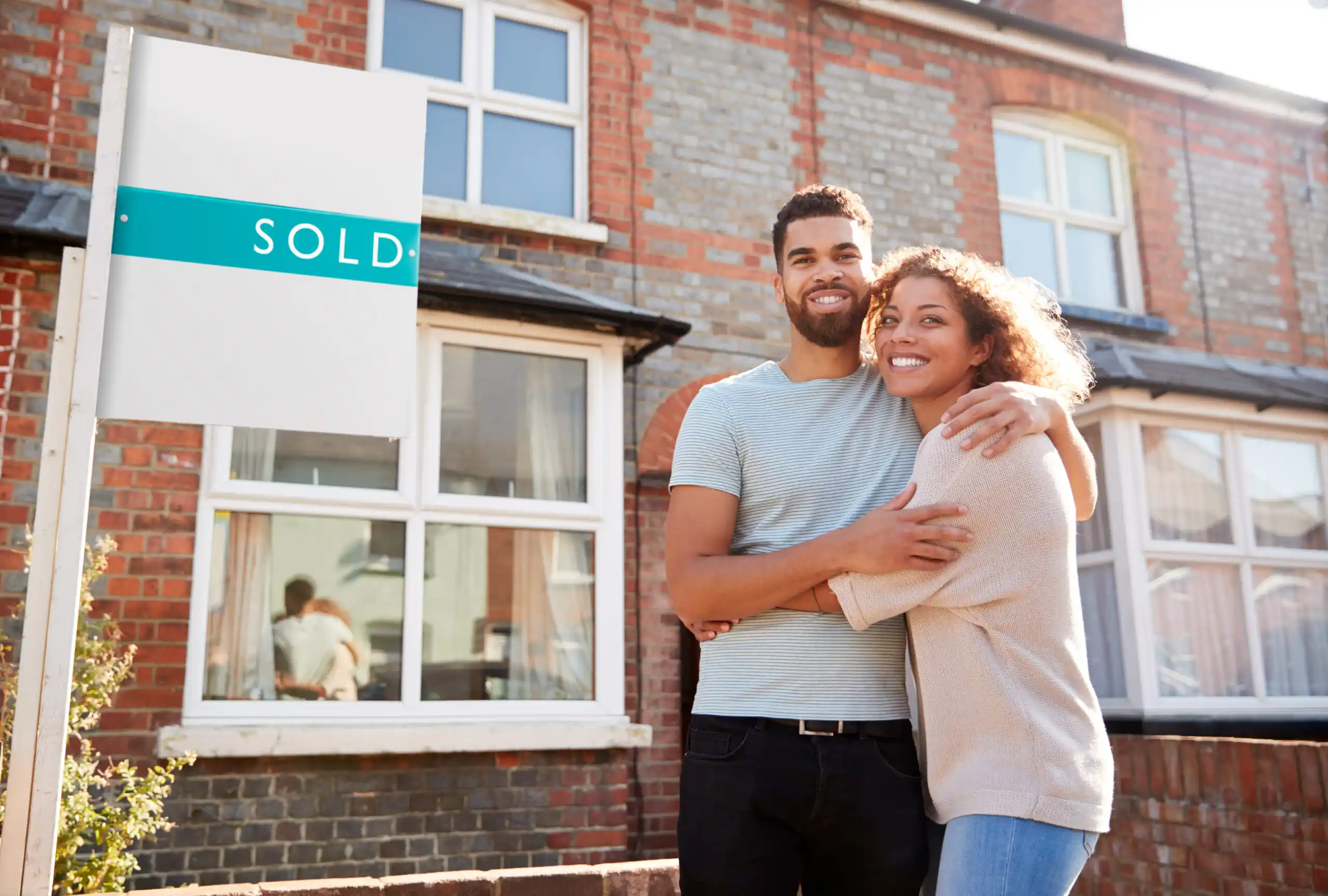 Happy Couple by Sold Real Estate Sign