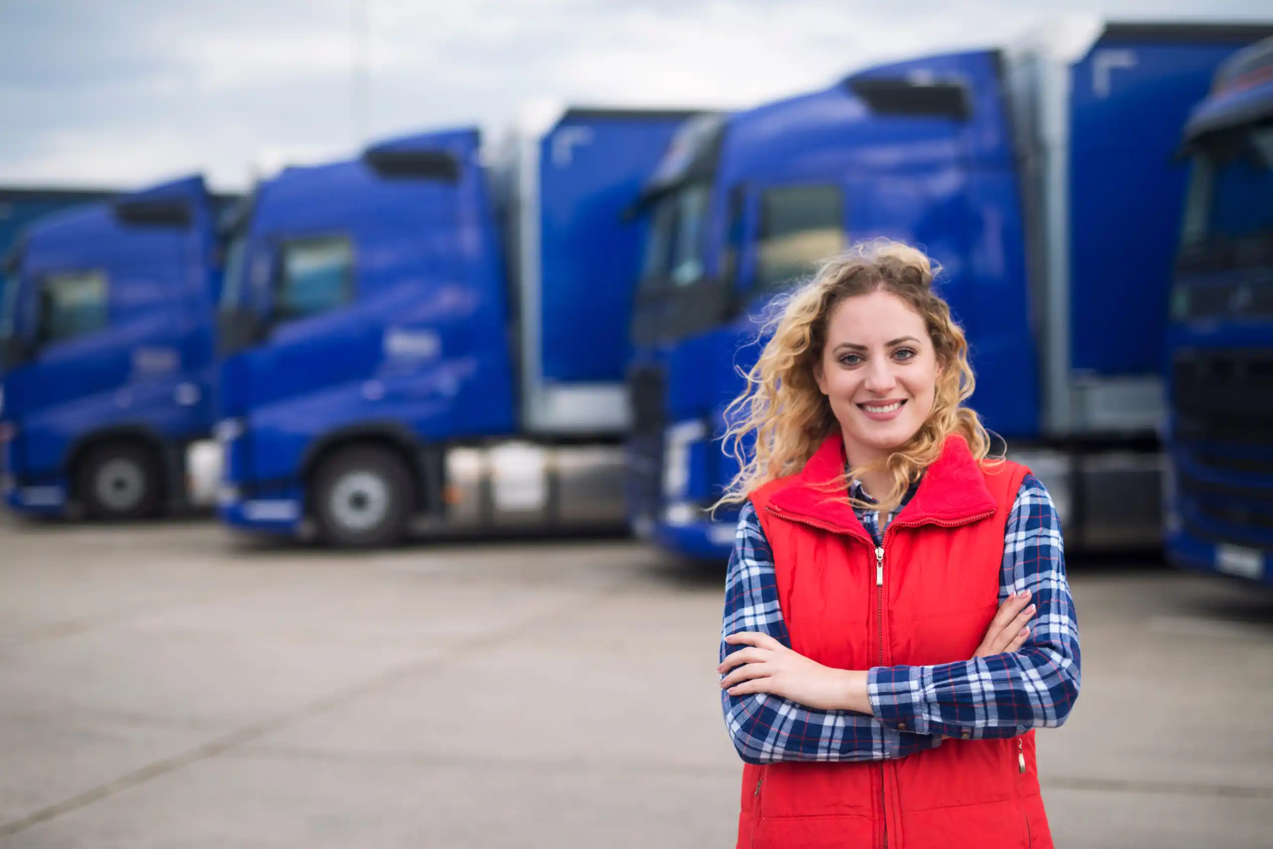 Female Trucker Smiling in Front of Trucks