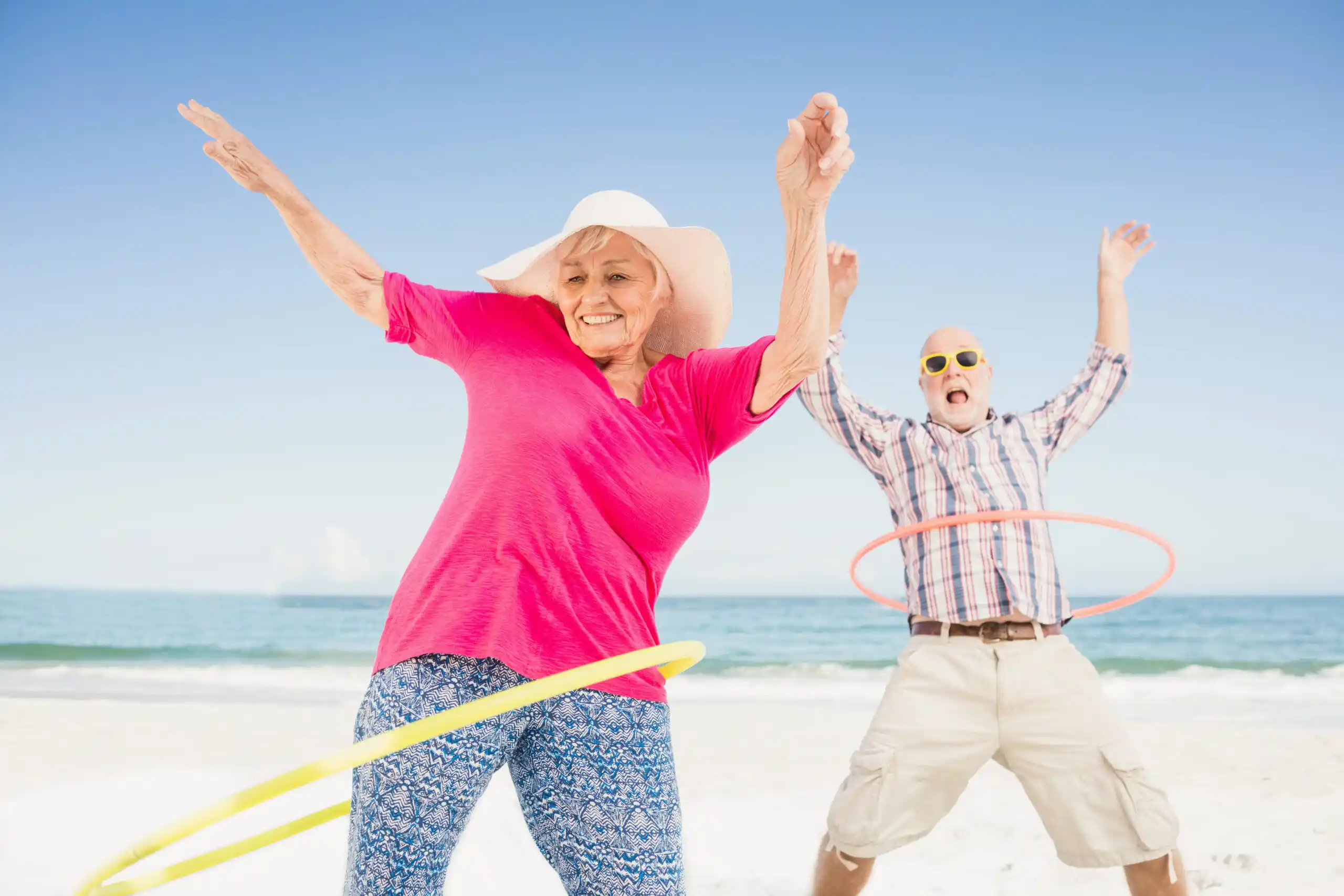 Retired Couple Hula Hooping on Beach