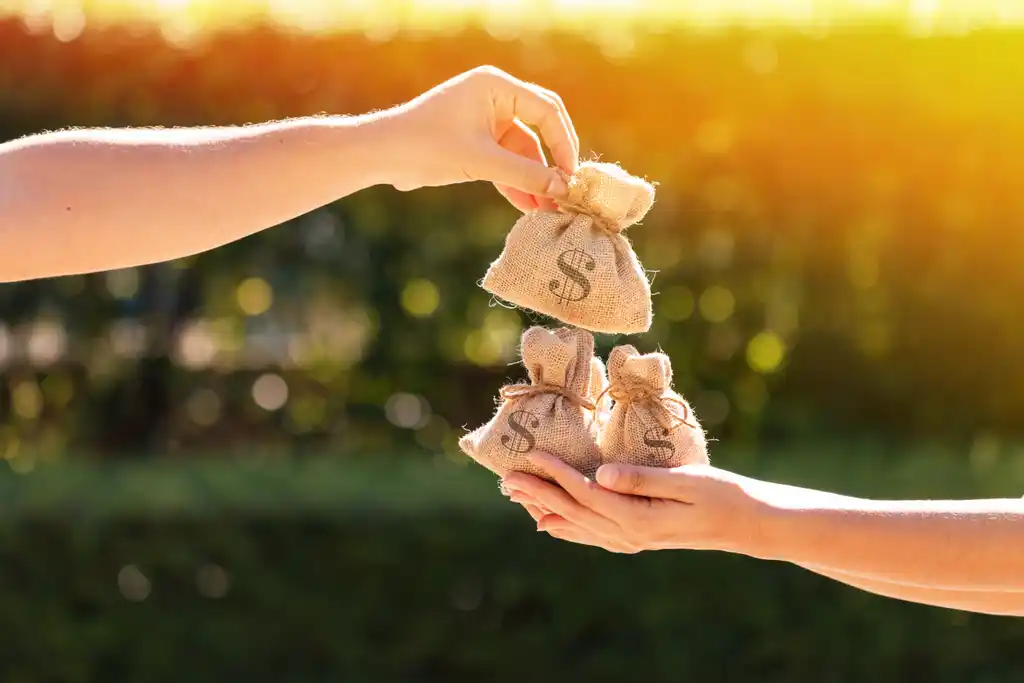 Person Handing Another Person Bags of Money