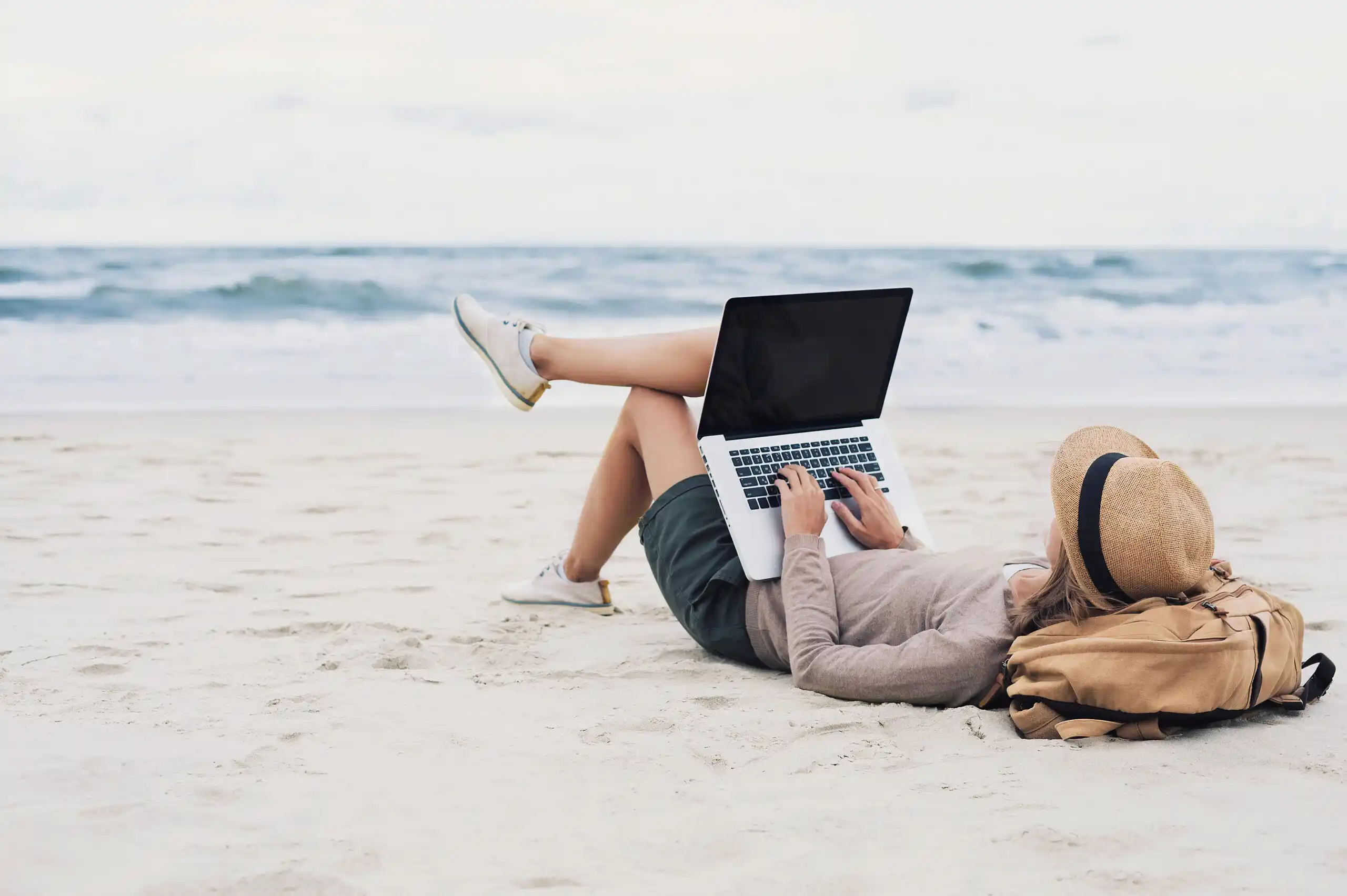 Freelancer Lounging on the Beach Working on a Computer